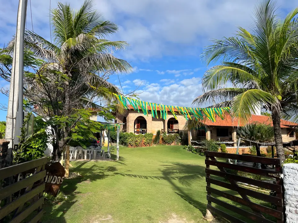Jardim com coqueiros e o portão de entrada