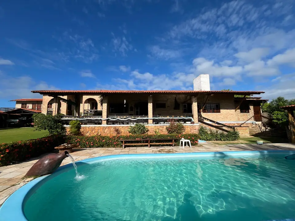 Piscina azul-turquesa diante da casa de tijolos com telhado colonial